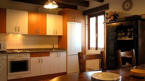 Una cucina con mobili in legno, un fornello, un frigorifero e un tavolo da pranzo con piatti.