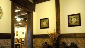 A room with a stone fireplace, wooden beams, and a dining area with chairs.