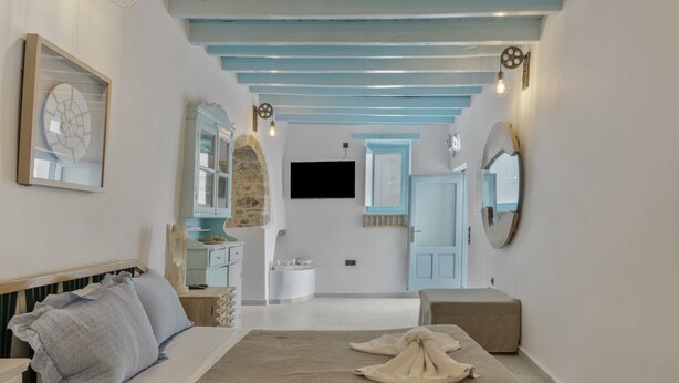 A bedroom with a bed, a dresser, a mirror, and a television.