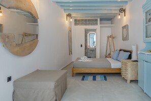 A bedroom with a bed, a bedside table, a dresser, a mirror, and a hanging light fixture. - Apartment 'For Two' with Balcony and Wi-Fi (Astypalaia)