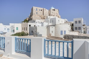 A coastal town with white buildings, a prominent stone tower, and a clear blue sky.