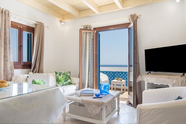 A room with a balcony, a TV, a dining table, and a sofa.
