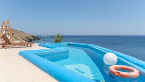 A swimming pool with a lifebuoy, a wooden swing set, and a palm tree by the sea. - Apartment 'Sea View Studio' with Sea View, Wi-Fi and Air Conditioning (Astypalaia Town)