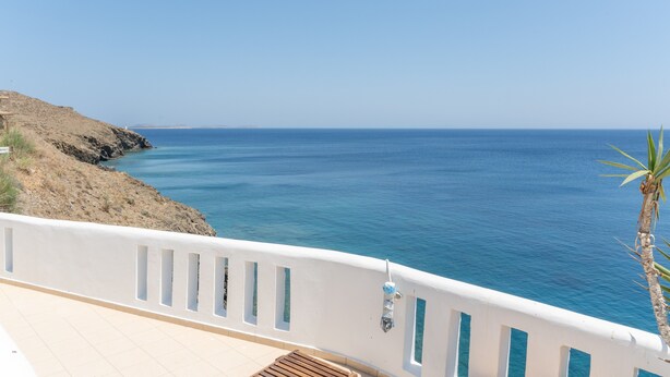 A coastal view with a white balcony, a clear blue sea, and a rocky cliff. - Apartment 'Sea View Studio' with Sea View, Wi-Fi and Air Conditioning (Astypalaia Town)