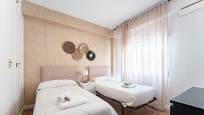 Ein Hotelzimmer mit zwei Betten, einer Holzwandverkleidung, einem Nachttisch mit Lampe und einer schwarzen Kommode.