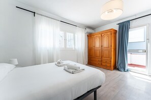 A bedroom with a bed, a wooden wardrobe, a window with curtains, and a balcony with a blue curtain. - Apartment 'Beachside Centre 6pax' with Private Terrace, Wi-Fi and Air Conditioning (Fuengirola)
