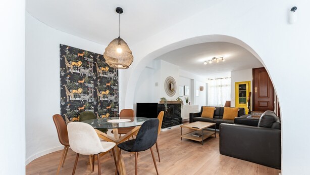 Ein moderner Wohnbereich mit Essbereich, Kamin, Sofa und einem markanten, bogenförmigen Durchgang.