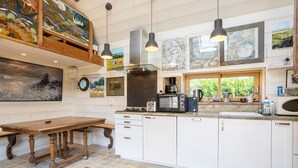 A kitchen with white cabinets, a wooden table, a microwave, and various kitchen appliances.