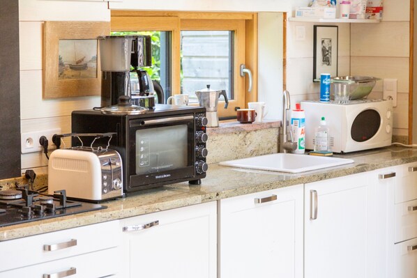 Una cocina equipada con estufa, tostadora, microondas y cafetera.