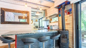 Una cocina moderna con una isla central, taburetes de bar, una estufa y un ventanal grande.