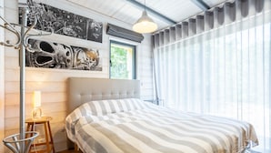 Un dormitorio con cama, lámpara, silla y cuadros en la pared.