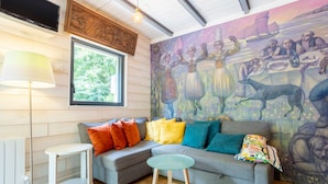 Un salón acogedor con un sofá modular, una mesita auxiliar, una lámpara y un mural en la pared.