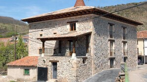 A stone building with a tiled roof, balconies, and a chimney.