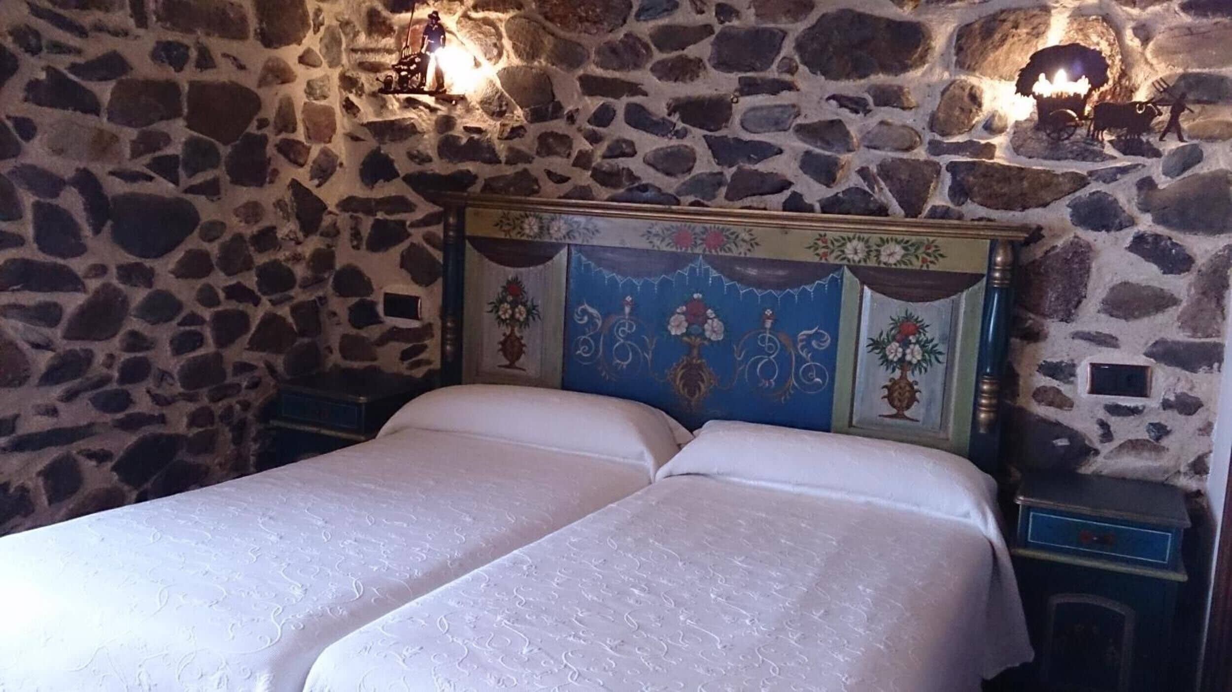 A double bed with a stone wall backdrop and decorative headboard.