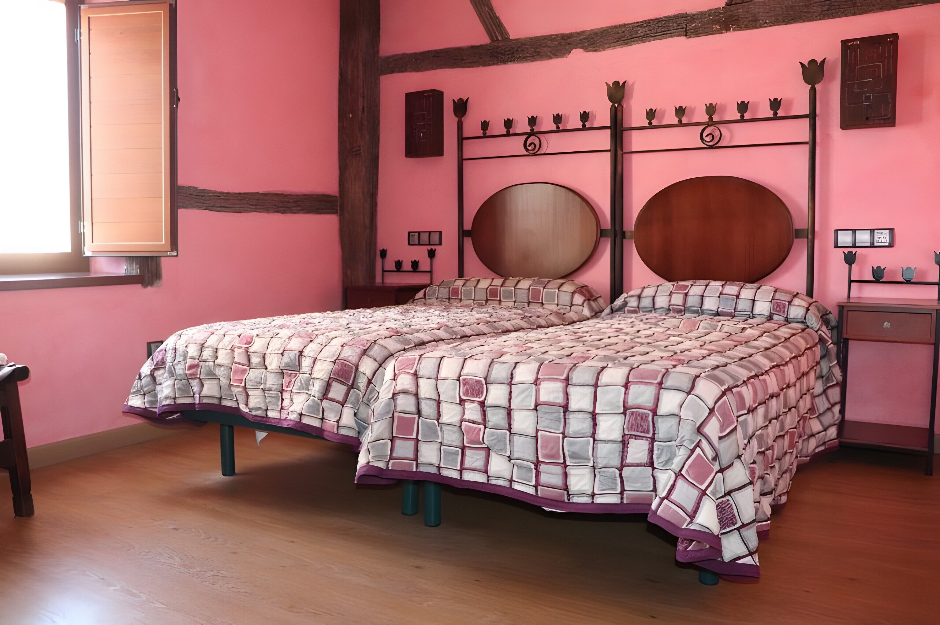Ein Schlafzimmer mit einer rosa Wand, einem hölzernen Bettgestell, einem runden Spiegel und einem Nachttisch.