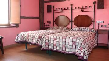 Ein Schlafzimmer mit einer rosa Wand, einem hölzernen Bettgestell, einem runden Spiegel und einem Nachttisch.