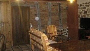Un interior de madera con una pared de piedra, un sofá, una mesa y un televisor.