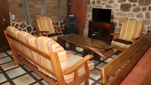 Una sala de estar acogedora con un sofá, sillas, una mesa de centro, chimenea y televisor.
