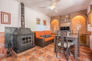 Una sala de estar acogedora con chimenea, un sofá, una mesa de comedor y un ventilador de techo.