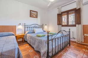 Un dormitorio con dos camas, una ventana con cortinas, un cuadro en la pared y un radiador.