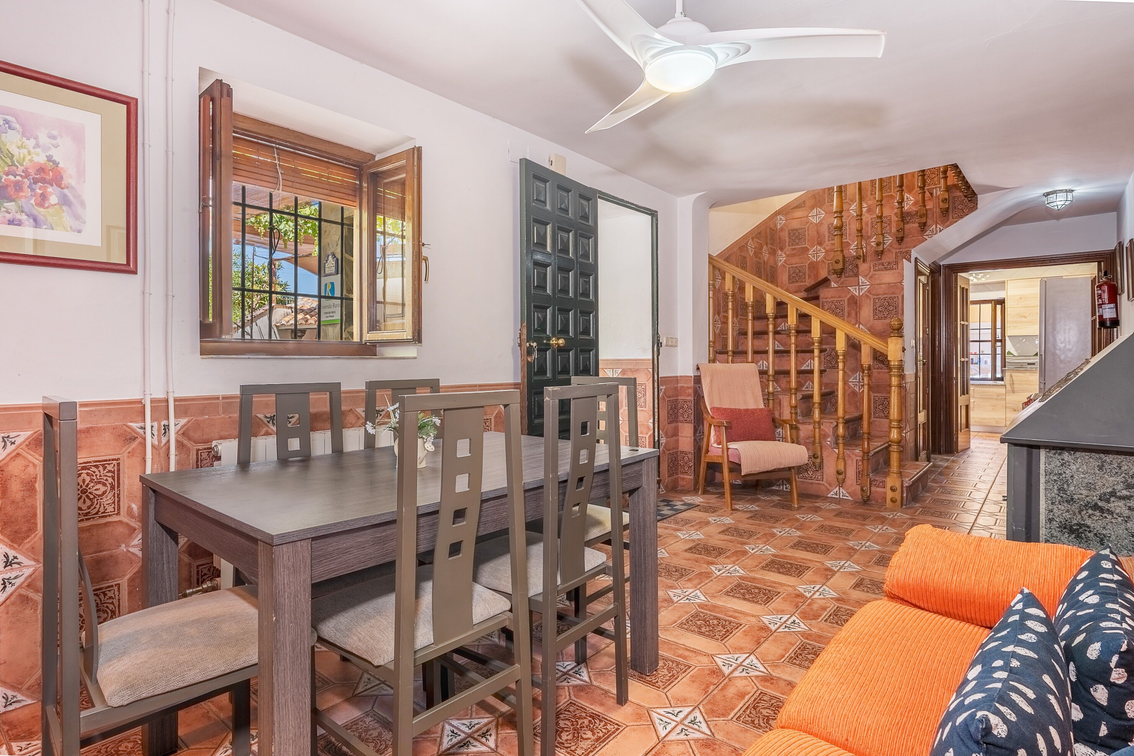A dining area with a table and chairs, a staircase, and a sofa.