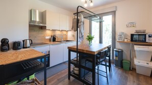 Una cocina moderna con encimera de madera, electrodomésticos de acero inoxidable y una estantería de metal negro.