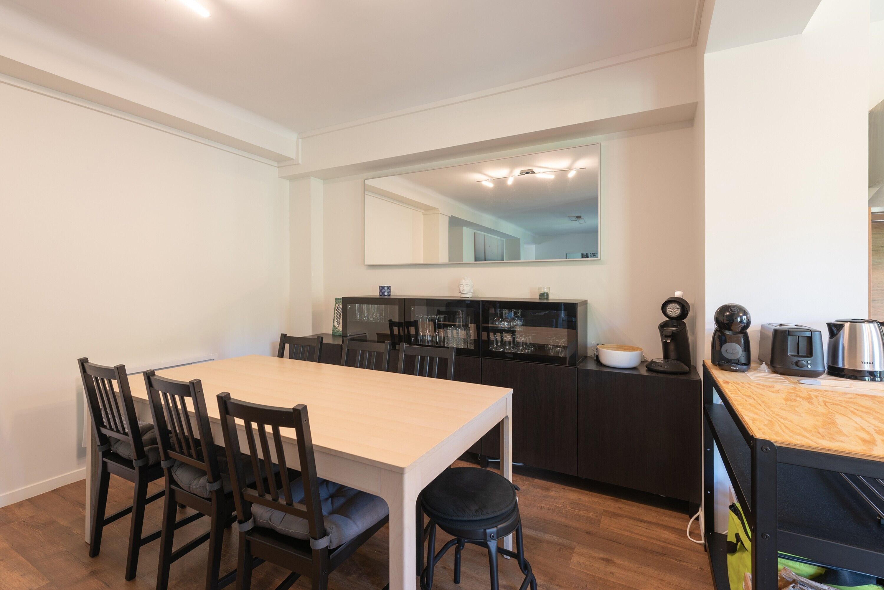 Een compacte keuken met een eethoek, inclusief een tafel, stoelen en een aanrecht met apparatuur.