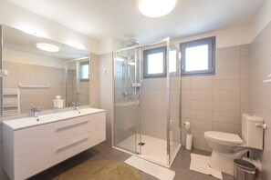 Regadera, secadora de cabello, pantuflas, papel de baño 