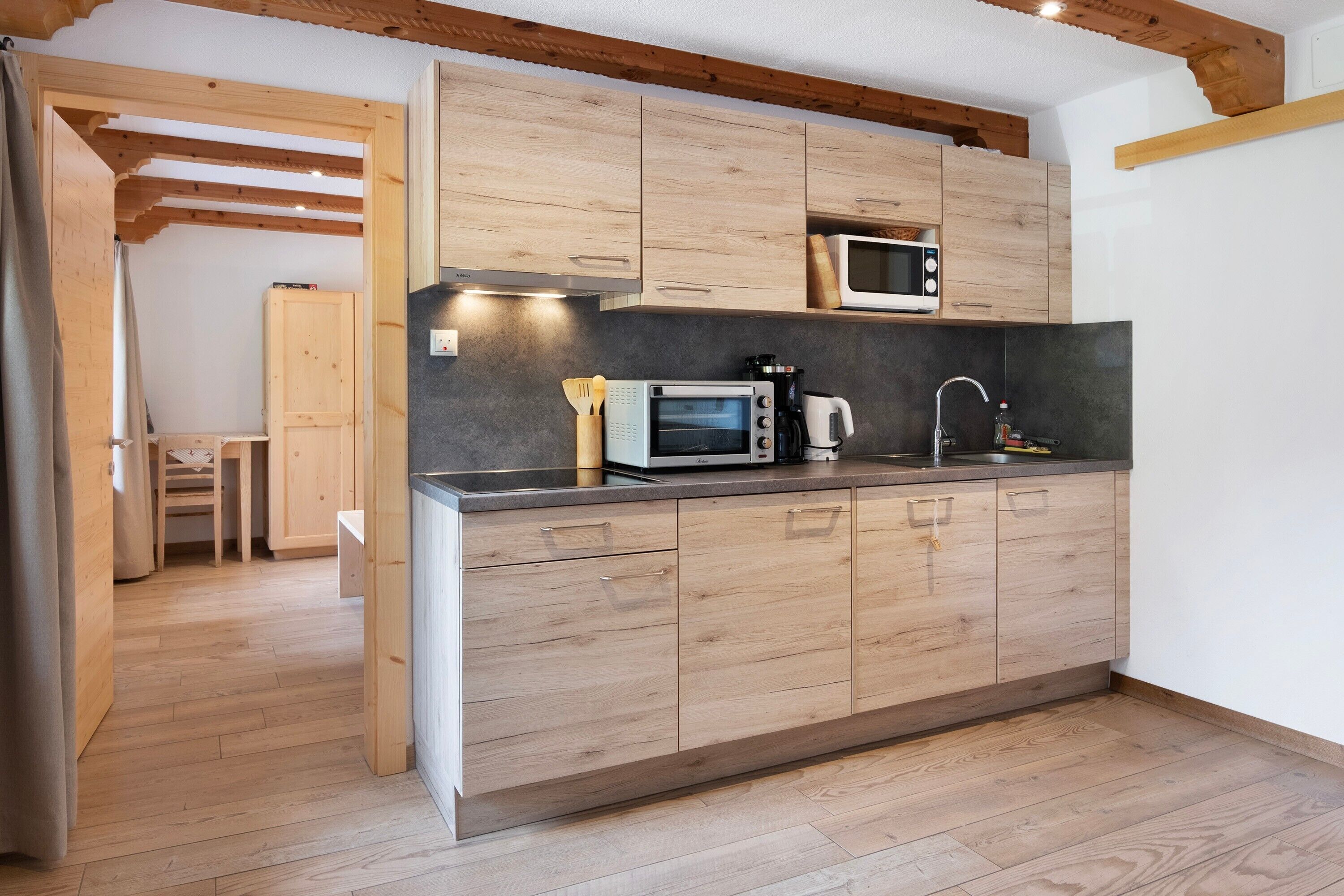 A modern kitchen with wooden cabinets, a microwave, a coffee maker, and a sink.