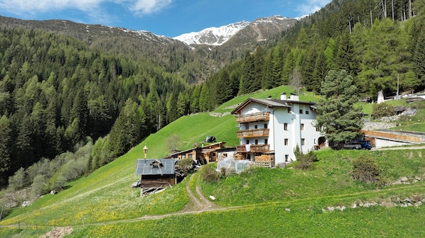A mountain house with a wooden exterior, a balcony, and a view of snow-capped mountains.