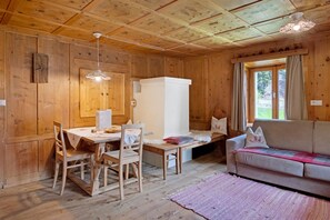 Un intérieur en bois comprenant une table à manger, des chaises, un canapé et une fenêtre avec des rideaux.