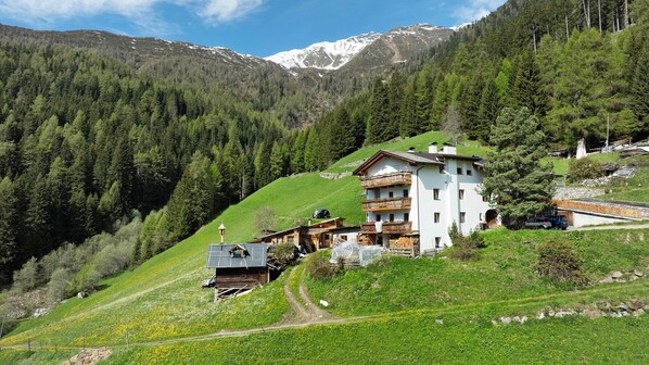 Une maison de montagne avec une façade en bois, un balcon et une vue sur des montagnes enneigées.