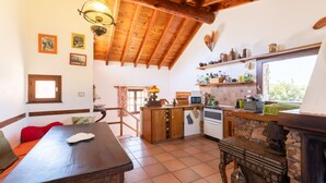 A rustic kitchen with wooden beams, a stone fireplace, and a dining area with a wooden table and chairs.