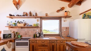 A kitchen with wooden cabinets, a stove, a microwave, and a window with a view.