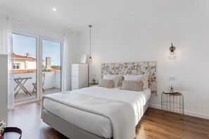 Un dormitorio con una cama grande, una mesita de noche, una lámpara y vistas al exterior.