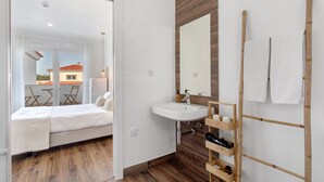 Un baño moderno con tocador de madera, un lavabo blanco y un espejo grande.