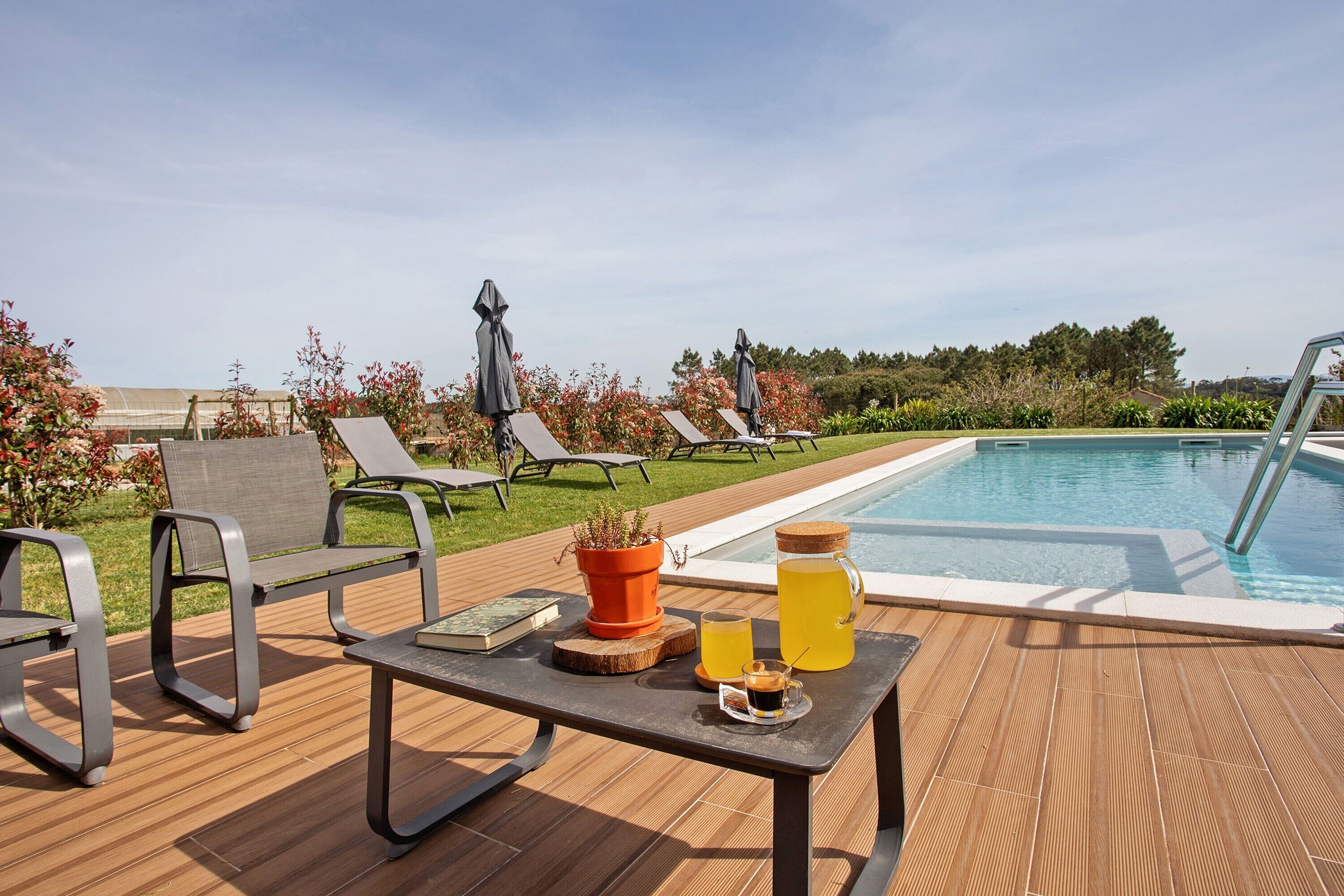 A poolside area with lounge chairs, a table with drinks, and a view of the pool.