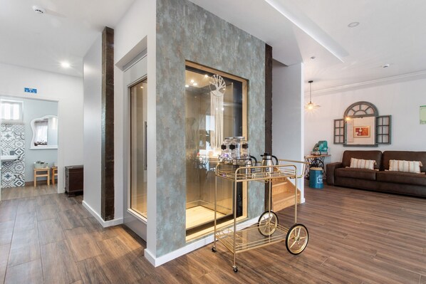 A modern living room with a glass partition, a coffee cart, and a sofa.