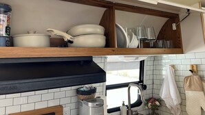 Eine kompakte Küche mit schwarzem Arbeitsplatz, einem eingebauten Backofen und einem Fenster über der Spüle.