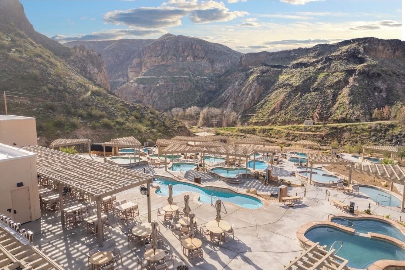 A resort with multiple swimming pools, outdoor seating areas, and a mountainous backdrop.