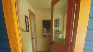 An entryway with a wooden door, a tiled floor, and a small display shelf with items.