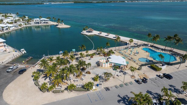 Eine Vogelperspektive auf ein Resort mit großem Pool, Strand und einer in das Wasser ragenden Pier.