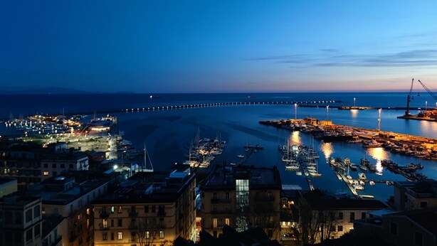 A coastal marina at dusk with boats docked, a bridge in the background, and buildings along the waterfront. - Dimora dei Naviganti - 15 Min from Amalfi Coast Sea View with Jacuzzi (Salerno)
