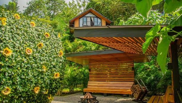 Uma casa moderna com deck de madeira, lareira e vegetação exuberante.