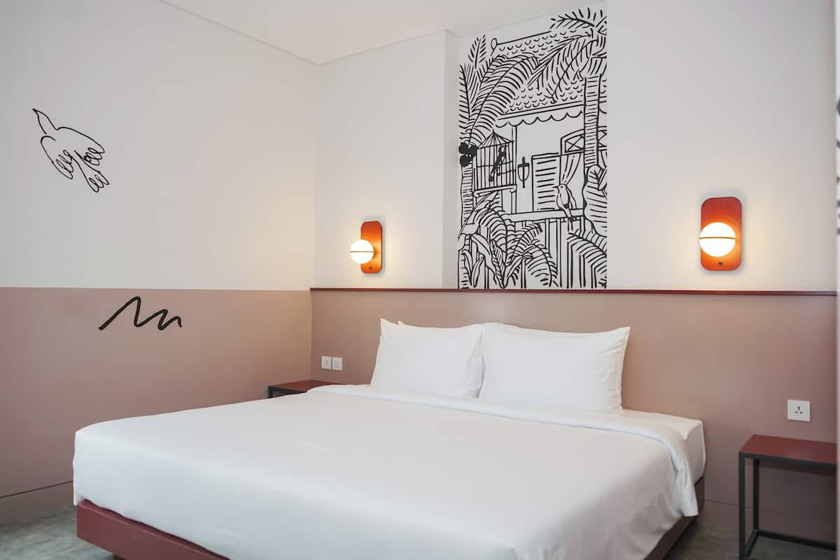 A bedroom with a bed, a wall with a hand-drawn design, and two wall-mounted lights.