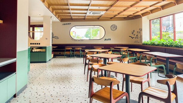 A restaurant interior with wooden ceiling panels, green and wooden tables, and chairs. - Kotta GO Hotel Tegal (Tegal)