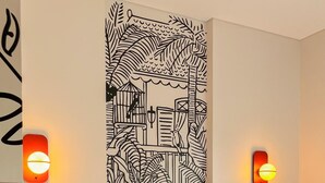 A hotel room with a bed, white bedding, a wall art piece, and two wall-mounted light fixtures. - Kotta GO Hotel Tegal (Tegal)