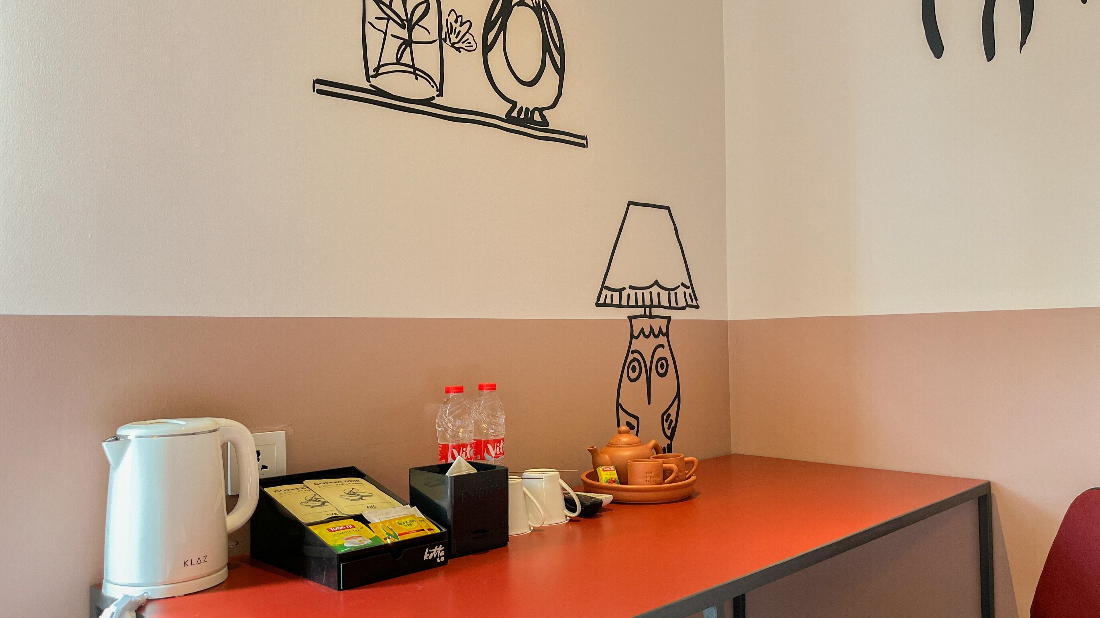 A table with a coffee maker, tea bags, and a teapot.