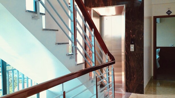 A modern interior with a glass staircase, a marble floor, and a door with a number plate. - Nha Nghi Thanh Binh 2 (Vinh Hung)