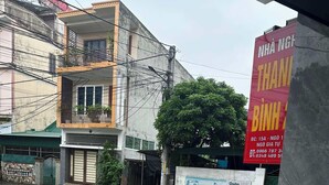 A street view with buildings, a large red sign, and a tiled pavement. - Nha Nghi Thanh Binh 2 (Vinh Hung)